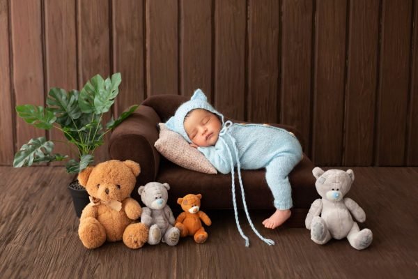 newborn-infant-little-likeable-pretty-baby-boy-sleeping-little-brown-sofa-blue-pijamas-surrounded-by-plant-toy-bears (1)